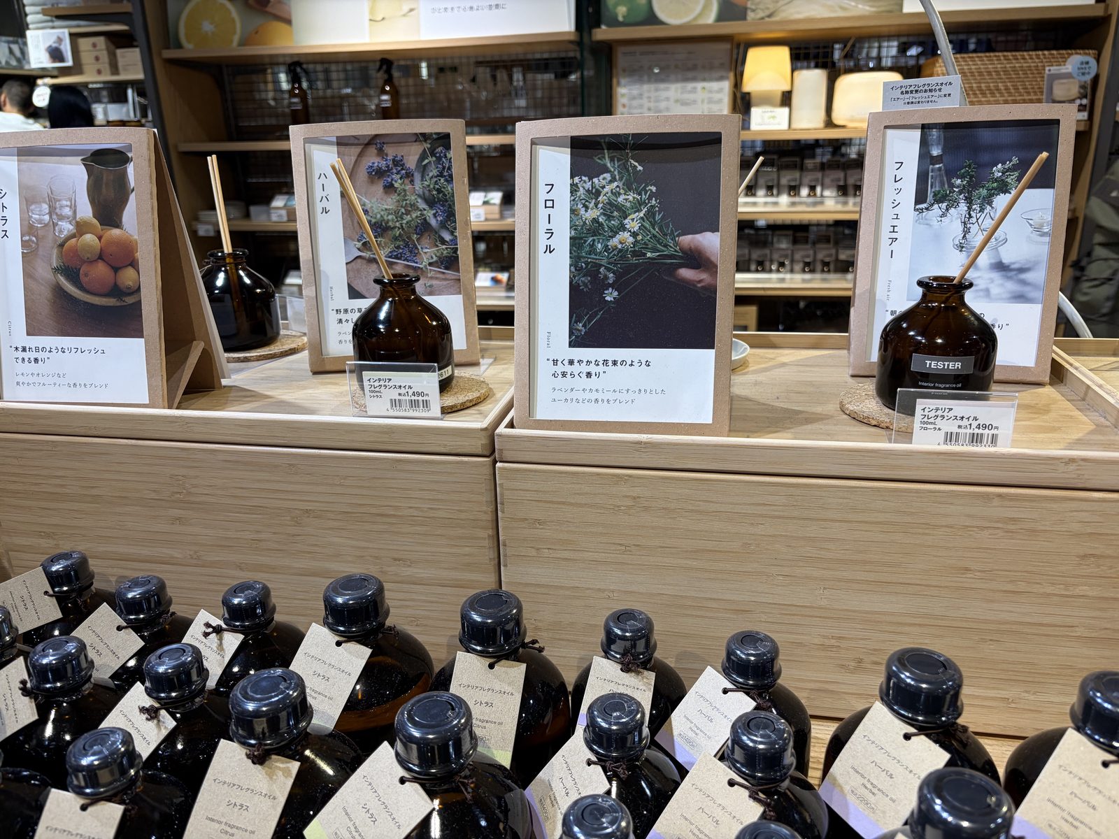MUJI interior fragrance display: amber glass diffuser bottles with citrus, herbal, floral and fresh-air scent lines